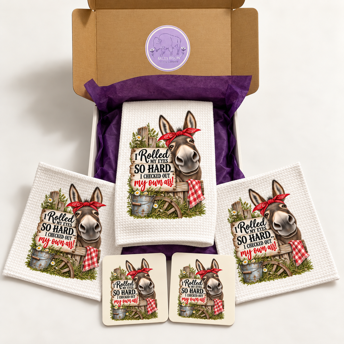 Funny donkey kitchen gift set with towel, two dishcloths and two coasters displayed with Salty Bison gift box
